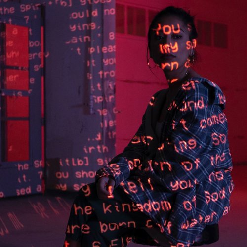 A woman sitting with words projected onto her face and clothes